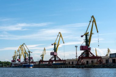 Venta Nehri 'nin kıyısında birçok uzun yük vinci duruyor. Havalandırma, Letonya, Baltık Denizi. Boşluğu kopyala