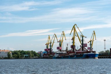 Venta Nehri 'nin kıyısında birçok uzun yük vinci duruyor. Havalandırma, Letonya, Baltık Denizi. Boşluğu kopyala