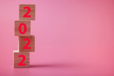 - Mutlu yıllar. Pembe arka planda 2022 numaralı tahta küp. 2022 yılının konsepti. Tatil tam gaz devam ediyor..
