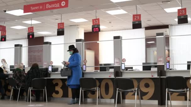 23,12,2020 Rus kadın kışın mavi bir tıbbi maske takan Moskovalı kadın MFC finans temalı belge ödemelerini işliyor. — Stok video