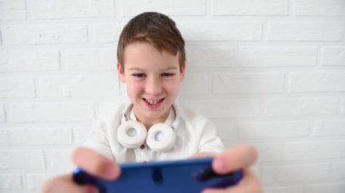 Genç, çocuk 11 yıl duygusal olarak mavi bir telefon çal, sinirlen, gülümse, beyaz bir arka planda yere otur.