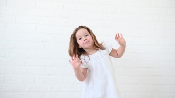 Kleines lustiges Mädchen, 4 Jahre alt, tanzt in einem weißen Kleid — Stockvideo