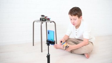 Genç çocuk 11 yaşında blogcu telefonda tasarımcı ve kulaklık takan arabalar hakkında yayın yapıyor.