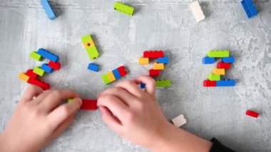 Yakın plan çocuklar 2022 numaralı bina numaralarını izole edilmiş gri arkaplandaki renkli yapı bloklarından alıyorlar.