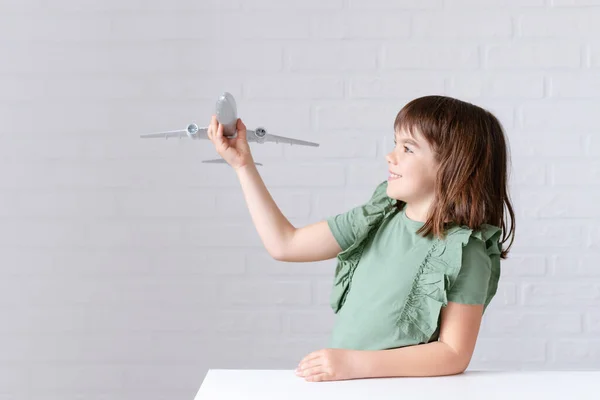 Feliz linda niña sonriendo jugando con avión sobre fondo blanco — Foto de Stock