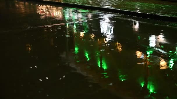 Pioggia notturna in città sulla strada in pozzanghere luci multicolori si riflettono — Video Stock