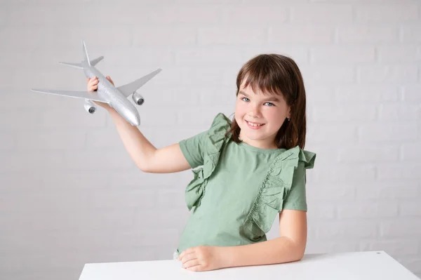 Feliz linda niña sonriendo jugando con avión sobre fondo blanco —  Fotos de Stock