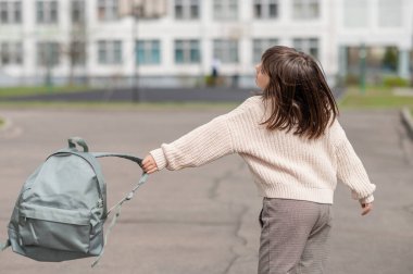 Mutlu kız 8 yıllık Avrupalı bir kız öğrenci okul bahçesinde yürüyor öğleden sonra sokakta kameraya yakından bakıyor.