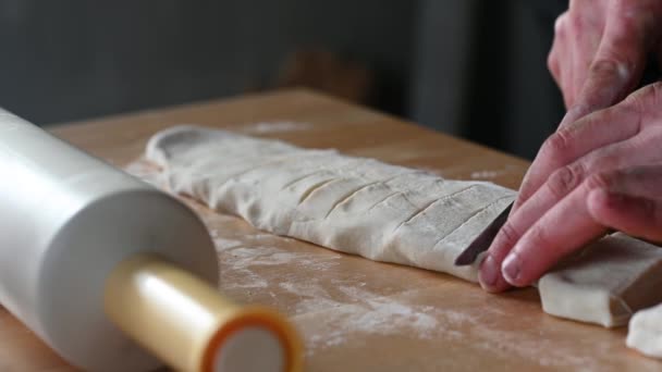Een deegroller ligt op tafel een man maakt deeg voor cheburateurs maakt ballen van deeg snijdt het deeg met een mes concept van zelfgemaakt voedsel — Stockvideo