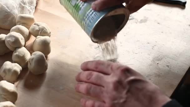 Um rolo de pino está na mesa um homem prepara massa para chebureks faz bolas de massa corta a massa com um conceito de faca de comida caseira — Vídeo de Stock