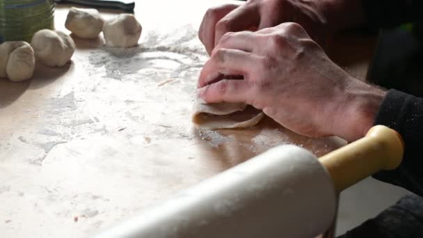 Un hombre en la cocina en casa prepara empanadas en la mesa, saca la masa, pone carne picada concepto de comida casera — Vídeo de stock