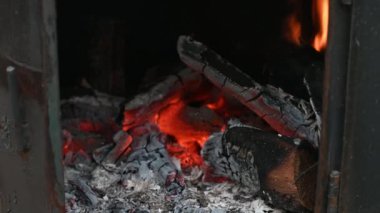Yazın yazlık bir evde, ocakta kırmızı bir alevle yanan odun, yeşil çimenlerin arka planında yanar.