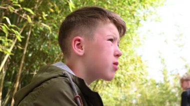 Okul çocuğu parkta oturmuş patlamış mısır yiyor.