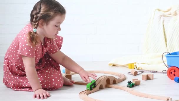 Linda niña pelirroja jugando con el ferrocarril de madera a casa — Vídeos de Stock