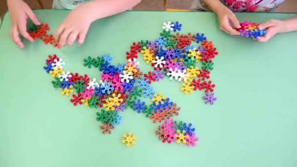 Niños juegan multicolor constructor brillante en la mesa en primer plano jardín de infantes — Vídeos de Stock