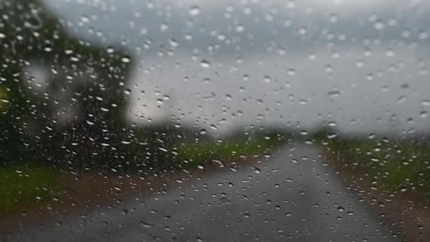 La vista desde la ventana del coche en el pueblo en los árboles verdes los pilares de la casa durante el día en la lluvia y el cielo gris rayo — Vídeos de Stock