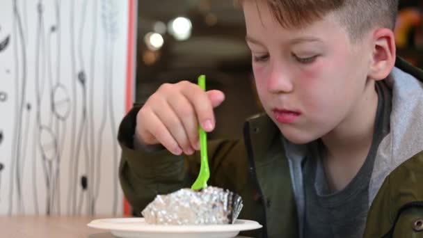 Хлопчик, який сидить у парку, їсть вуличну їжу крупним планом — стокове відео