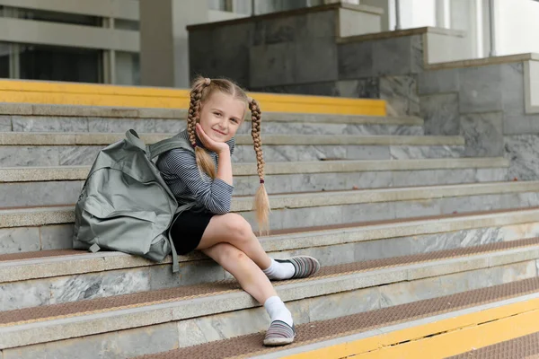 Милая счастливая девочка школьницы с рюкзаками играют рядом со школой — стоковое фото