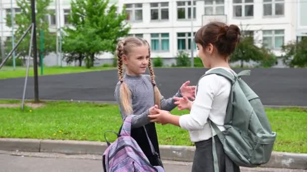 Két aranyos boldog lány iskolás lányok hátizsákkal játszanak az iskola közelében — Stock videók