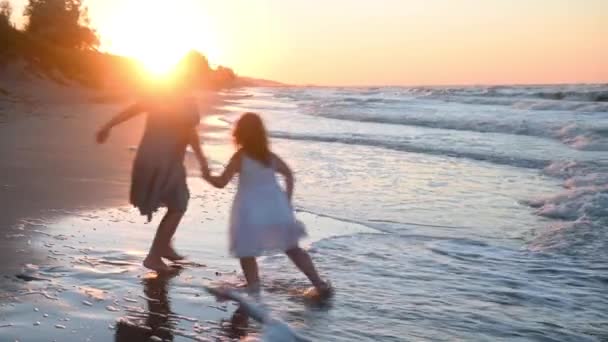 Kislány gyermek egy hosszú sundress hosszú haj fut végig a tengerparton naplementekor nyáron — Stock videók