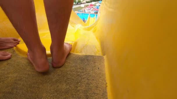 한 남자가 여름에 워터 파크에서 노란색 슬라이드를 타고 내려가는 모습 — 비디오