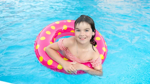 Niedlichen lächelnden Mädchen in einem hellen Kreis schwimmt auf dem Hintergrund eines blauen Pools im Sommer — Stockfoto