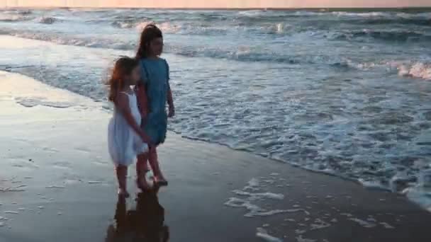 長い髪をした長いサンドレスを着た少女が夏の日没に海沿いのビーチを走り — ストック動画