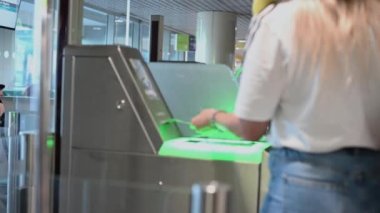 Tıbbi maskeli insanlar havaalanından ellerinde biletlerle ve bavullarıyla turnikeden geçiyorlar.