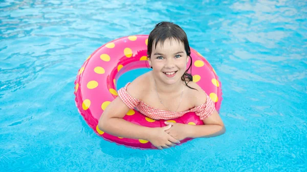 Parlak bir çemberdeki tatlı, gülümseyen kız yazın mavi bir havuzda yüzer. — Stok fotoğraf