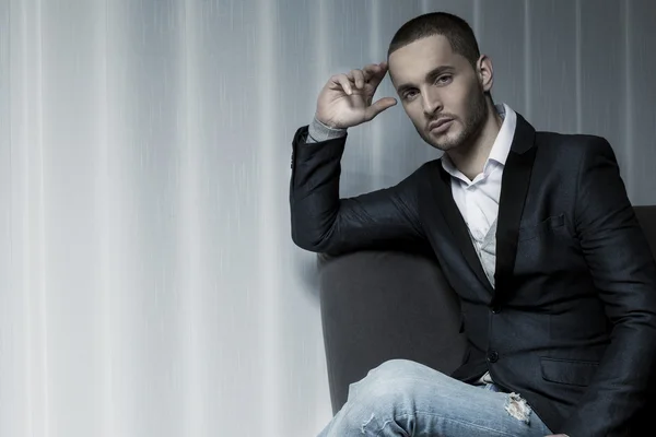 Young business man sitting on a chair and looking at the camera — Stock Photo, Image