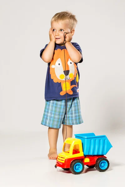 Assustado menino brincando com o grande carro de plástico — Fotografia de Stock