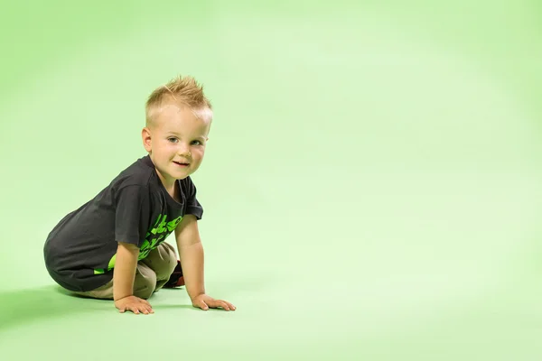 Glücklicher kleiner blonder Junge sitzt, grüner Speck — Stockfoto