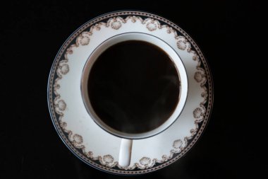 Siyah arkaplanda süsleri olan zarif bir kahve fincanı.