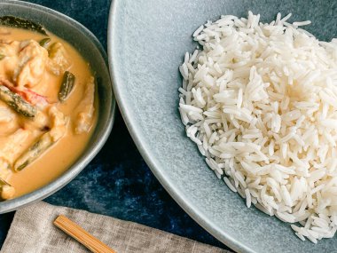 Kırmızı Tayland usulü körili tavuk. Tabakta sos. pirinç ayrı tabakta pastel mavi tabakta, yemek çubukları peçete yüksek açılı, kapat.