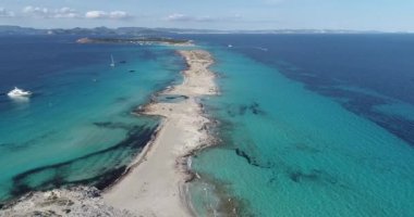 Etrafında deniz olan nokta şekilli plaj ve arka planda İbiza adası.