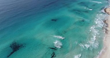Turkuaz suları ve dalgaları olan inanılmaz bir sahil, insansız hava aracından görülüyor.