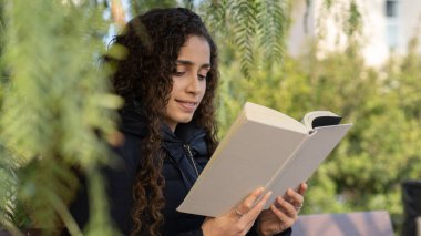Parktaki genç Brezilyalı kız elinde kitapla
