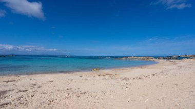 Şeffaf turkuaz suyu ve güneşli bir günde mavi gökyüzü olan cennette bir sahil..