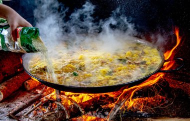 Geleneksel Valensiyalı paella pişirme süreci: İspanya 'daki kaynayan Akdeniz mutfağına pirinç eklemek.