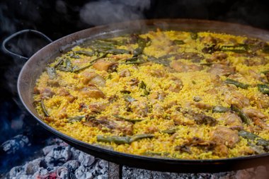 Geleneksel Valensiyalı paella: klasik kuru pirinç dokusunu ve Akdeniz sunumunu gösteren bitmiş yemek.