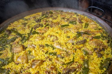 Geleneksel Valensiyalı paella: klasik kuru pirinç dokusunu ve Akdeniz sunumunu gösteren bitmiş yemek.