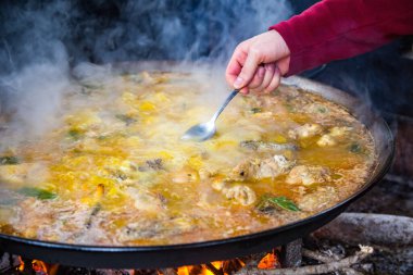 Geleneksel Valensiyalı paella pişirme süreci: İspanya 'da tuz seviyesindeki Akdeniz mutfağını kontrol etmek için çorba tatmak.