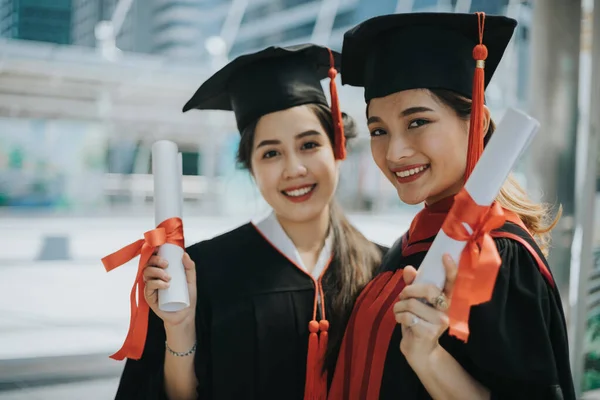 Mezun olan mutlu öğrenci, elinde diplomalar ve altın para ile.