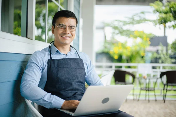 Kafeteryada dizüstü bilgisayarla oturan mutlu bir iş adamı.
