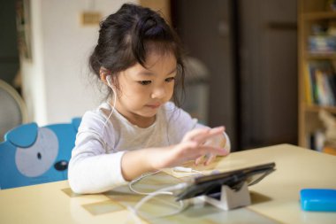 Asyalı kız evde alfabe öğreniyor. Yeni normal. Covid-19 koronavirüs. Sosyal uzaklık. Evde kal.