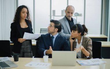 Ciddi uluslararası çeşitli iş adamları finansal sonuç değerlendirmesini dizüstü bilgisayarla tartıştılar.