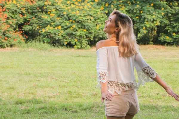 Güzel, mutlu bir kadın parkta gülüp eğleniyor.