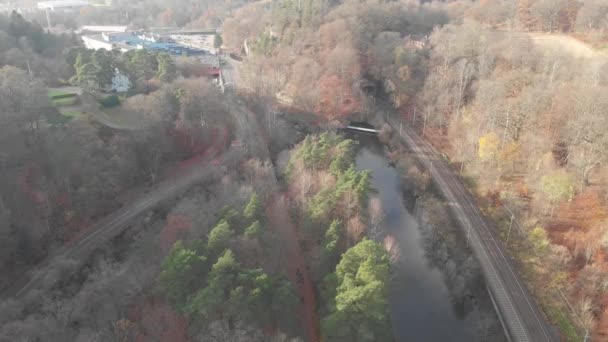 Spoorweg langs het waterkanaal, herfstlandschap, onvruchtbaar bos, achterwaartse antenne — Stockvideo