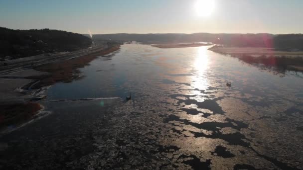 Raggio di sole sullo scioglimento del ghiaccio sul fiume, riflessione sulla superficie, tramonto, tirare indietro aerea — Video Stock