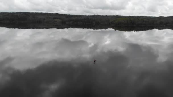 Una sola barca in canoa sul lago calmo con riflessione nuvola, aerea — Video Stock